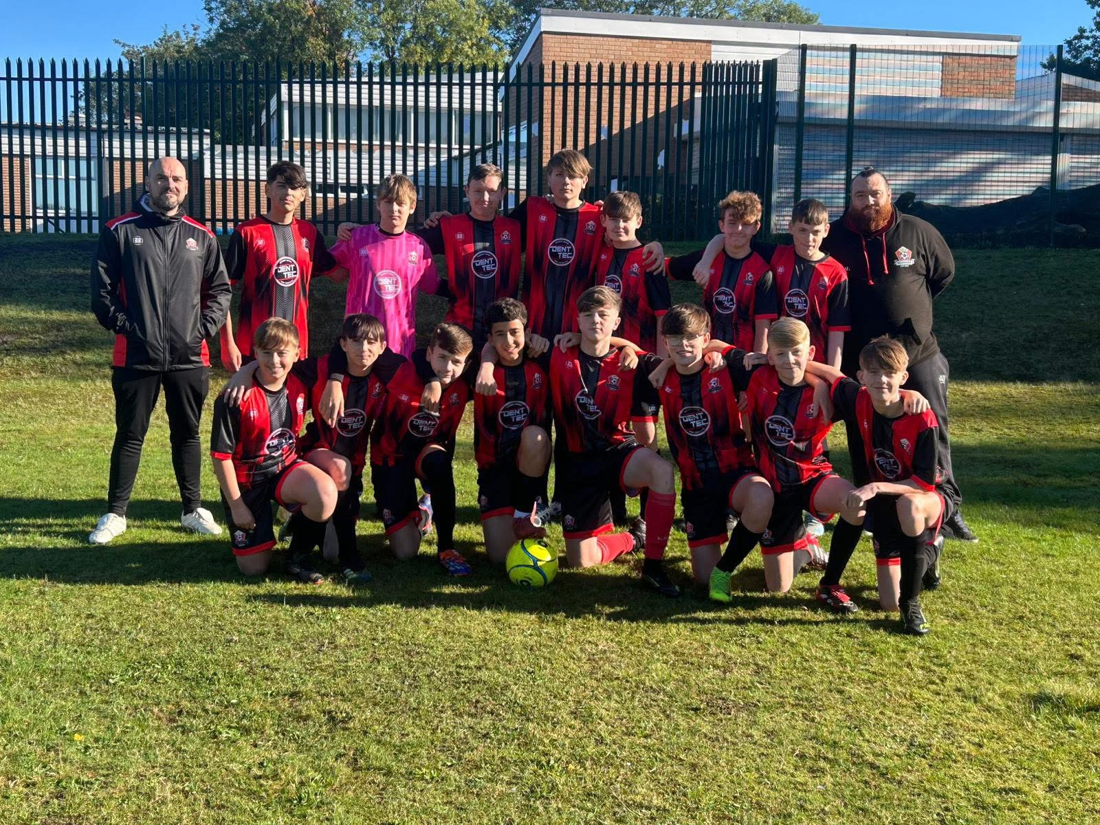 Youth football team and coaches in red and black kits