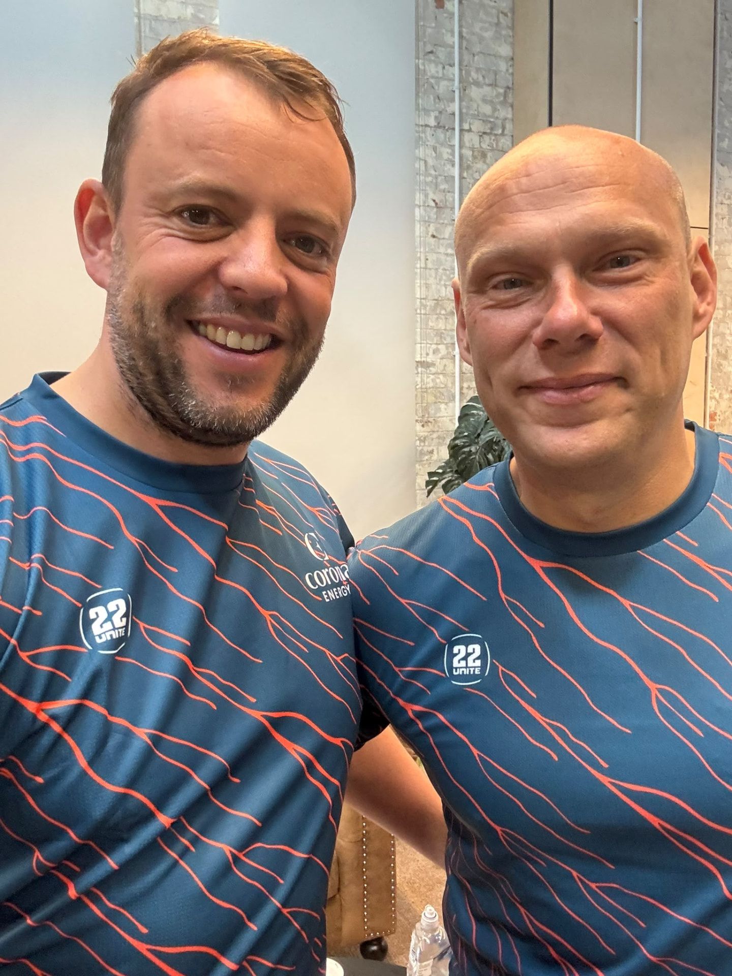 Two men in navy 22 Unite training shirts with coral print